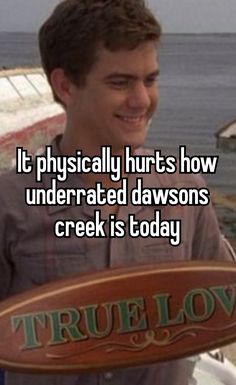 a man holding a sign that says it physically hurts how underrated dawsons creek is