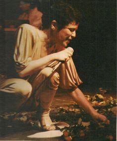 a man kneeling down on top of a surfboard next to a pile of leaves