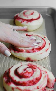 a woman's hand reaching for some food on a baking sheet