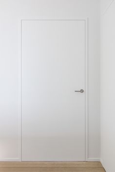 an empty room with a white door and wooden floor