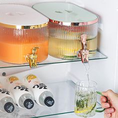 a person is pouring drinks from a faucet into a glass on a shelf