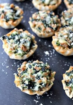 mini pizzas filled with spinach and cheese on a black surface