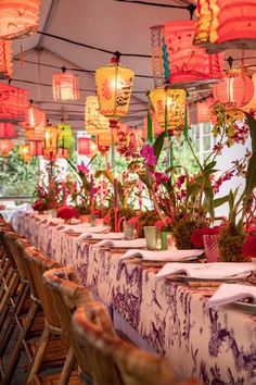 an outdoor dining area with tables and chairs covered in lanterns, flowers and vases