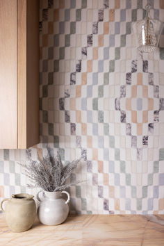 two vases are sitting on the counter in front of a wall with a checkered pattern