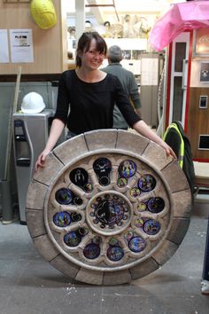 a woman standing next to a large circular object made out of glass and marbles