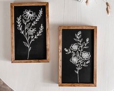 two framed flowers are sitting on a table