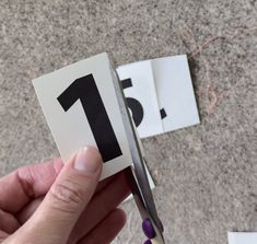 someone is cutting out the number one card with scissors