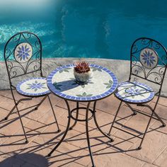 an outdoor table and chairs next to a swimming pool with a potted plant on top