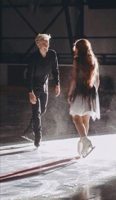 a man and woman are walking on an ice rink with one holding the other's hand