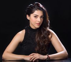 a beautiful young woman sitting at a table with her hands on her hips and looking off to the side