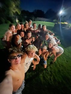 a group of young people posing for a photo at night in the grass with their arms around each other