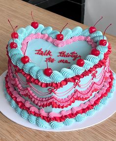 a heart shaped cake with cherries on the top is sitting on a wooden table