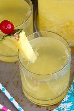 two glasses filled with pineapple juice and topped with a cherry on the rim,