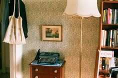 an old fashioned typewriter sitting on top of a wooden table next to a lamp