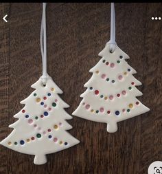 two white ceramic christmas trees hanging from strings