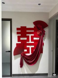 a red wall hanging on the side of a white wall next to a black door