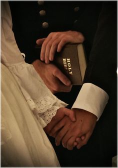 two people are holding hands over a book