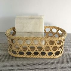 a wicker basket with a white towel in it sitting on a gray tablecloth