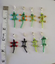 six small beaded cross pendants on a measuring tape next to a plastic ruler