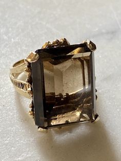 Huge Beautiful 14k gold smokey Quartz stone Leaf swirl design Size 5.5-5.75. See photos for exact measurements Real Smokey Quartz. Solid 14k gold. Ring has no markings. Ring tested at 14k Stone is rectangular in shape. Stone has no internal flaws and is clear translucent smokey quartz Pictures show a piece of gold sticking forward under the ring mount or under the stone. It is a piece thats there and thought to mention it as a flaw or unususl remarks. See photos with red arrow. It does not affect the intended purpose of the ring. Fits nice and has a heavy stone. The size of the stone can be compared to the size of a nickle. See photos Ring has a piece of metal hanging on the inside of the ring unseen and not touching the finger, see photos Ring is a heavy 11.62 grams This Smokey Quartz 14k Smokey Quartz Ring Engagement, Smokey Quartz Jewelry, Smokey Quartz Ring, Photo Ring, Quartz Engagement Ring, Ring Mountings, Leaves Design, Red Arrow, Gold Stone