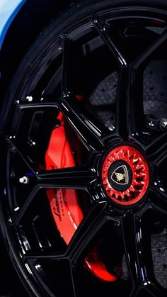 the front wheel of a sports car with red spokes and black rims on it