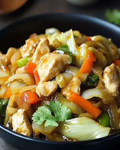 a bowl filled with chicken and vegetables on top of a table next to chopsticks