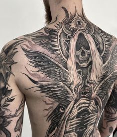 the back of a man with tattoos on his upper and lower half, showing an image of a demon