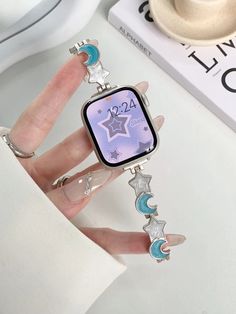 a woman's hand holding an apple watch with stars and moon charms