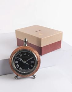 an alarm clock sitting on top of a table next to a box with a watch in it