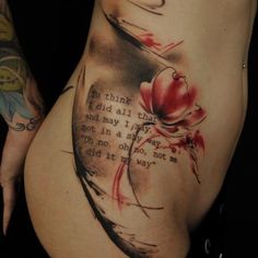 a woman's stomach with an inked quote on the side, and flowers