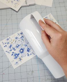 a person is using a machine to cut paper with flowers on the cutting board next to it