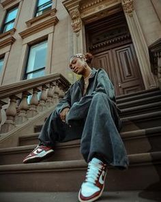 a woman sitting on the steps in front of a building talking on her cell phone