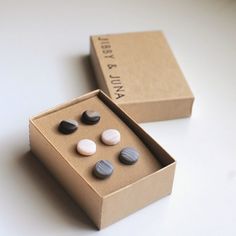 two small boxes with different colored rocks in them sitting on a table next to each other