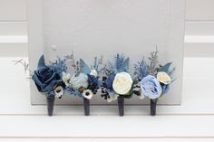 three blue and white flowers are placed on the side of a wall