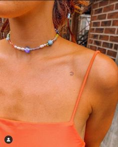 a woman in an orange top wearing a necklace