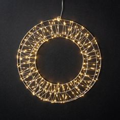 a christmas wreath with lights hanging from it's side on a black background,