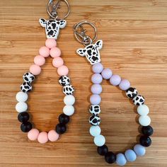 two bracelets with different colored beads and giraffe head charms on wooden surface