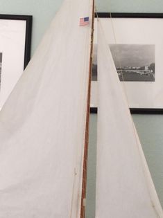 a model sailboat sitting on top of a table next to two framed pictures in a room