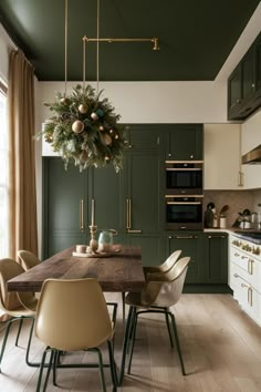 a kitchen with green walls and wooden table surrounded by chairs in front of an oven