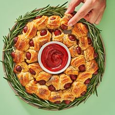 pigs in a blanket wreath with ketchup on top and rosemary sprigs