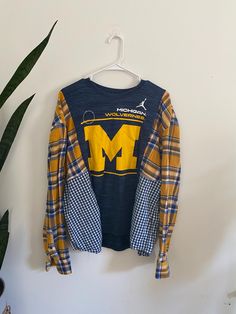 a blue and yellow plaid jacket hanging on a wall next to a potted plant