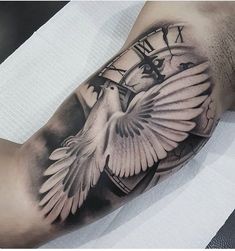 a man's arm with a clock and dove tattoo on it, which has roman numerals