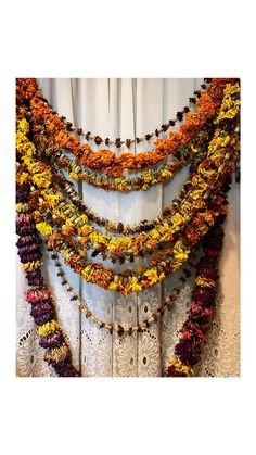 multicolored necklaces hanging from the side of a white curtain in front of a window