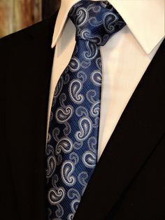 "Mens 100% silk blue paisley necktie. This Blue paisley tie features a navy background with blue ourlined with off white paisley pattern. Handmade from 100% silk, this special collection features a .75\" Eds Neckties logo at the bottom right front corner of every tie and a larger logo located on the tipping (Back of the tie). The label features the collection name (Nathaniel Alexandria) Named after my son Nathaniel and my daughter Alexandria. Expertly hand-made from 100% silk you can select your Purple Gothic, Make A Tie, Blue Necktie, Floral Necktie, Suit Ideas, Gold Tie, Goth Wedding, Paisley Tie, Fashion Suits For Men