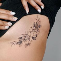 a woman's stomach with flowers and leaves tattoo on her side ribcage