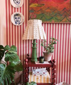 a green lamp sitting on top of a wooden table next to a potted plant