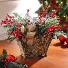 a basket filled with red berries and greenery next to christmas decorations on a table