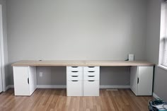 an empty room with two white cabinets and a hard wood floor in front of a window