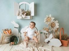 a baby is sitting in a chair surrounded by easter decorations and bunny figurines