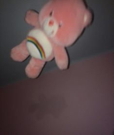 a pink teddy bear holding a white ball in it's mouth on the ceiling